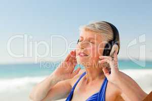 Senior woman listening to music at the beach