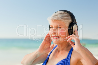 Senior woman listening to music at the beach