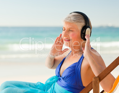 Retired woman listening to music at the beach