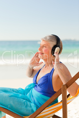 Retired woman listening to music at the beach