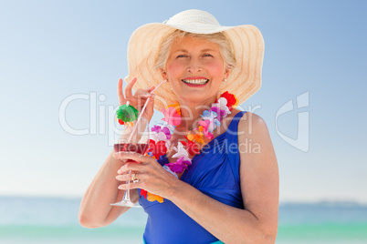 Elderly woman drinking a cocktail on the beach
