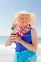 Elderly woman drinking a cocktail on the beach