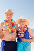 Senior couple drinking a cocktail on the beach