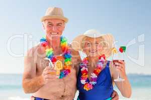 Senior couple drinking a cocktail on the beach