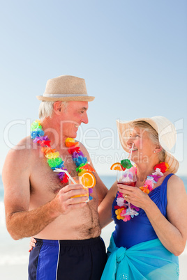 Senior couple drinking a cocktail on the beach