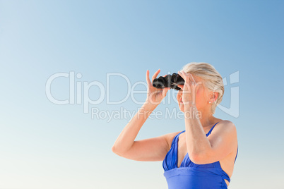 Senior woman bird watching at the beach