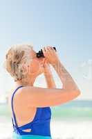 Senior woman bird watching at the beach