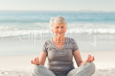 Senior woman practicing yoga on the beach