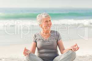 Senior woman practicing yoga on the beach