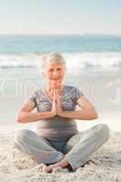 Senior woman practicing yoga on the beach