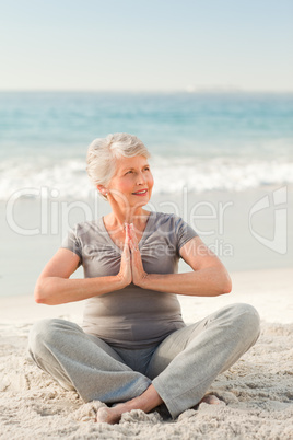 Senior woman practicing yoga on the beach