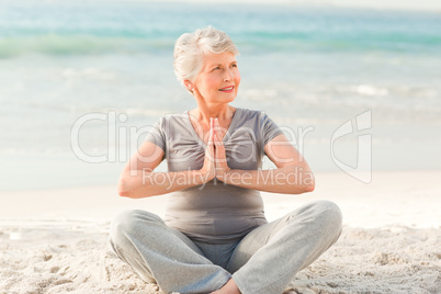 Senior woman practicing yoga on the beach