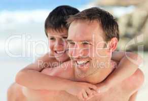 Father having son a piggyback on the beach