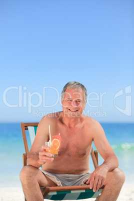 Senior man drinking a cocktail on the beach