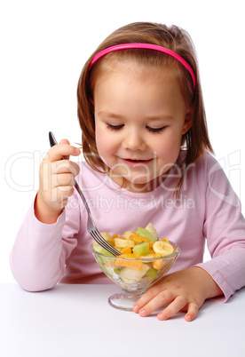 Little girl eats fruit salad