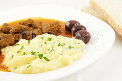Goulash with potato puree, olives and bread