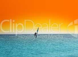 surfer on blue sea under orange sky