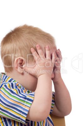 A blond small boy hold his hands on the face