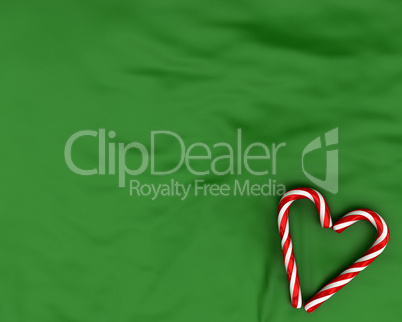 Heart made from christmas candies on green background