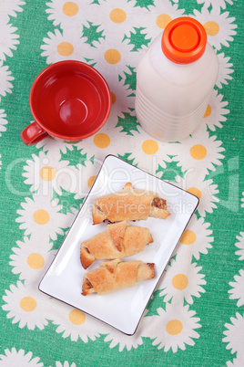 Plastic bottle with clabber, cup and bagels on tablecloth