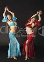 Two woman dance and smile in arabian costume