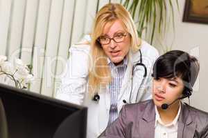 Female Doctor Discusses Work on Computer with Receptionist Assis