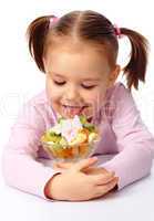 Little girl licks fruit salad