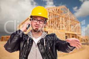 Young Cunstruction Worker on Cell Phone In Front of House