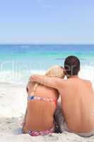 Man hugging his girlfriend while they are looking at the sea
