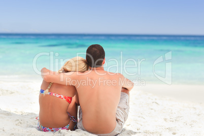Man hugging his girlfriend while they are looking at the sea
