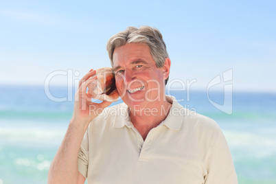 Senior man listening his shell