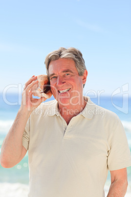 Senior man listening his shell