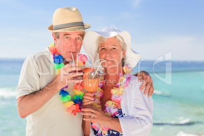 Elderly couple drinking a cocktail on the beach