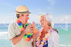 Elderly couple drinking a cocktail on the beach