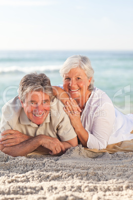 Elderly couple lying down on the beach