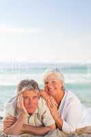 Elderly couple lying down on the beach