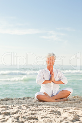 Mature woman practicing yoga on the beach