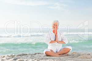 Mature woman practicing yoga on the beach