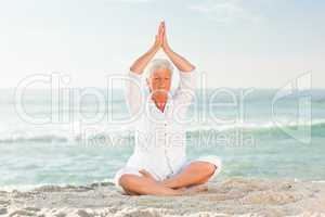Mature woman practicing yoga on the beach
