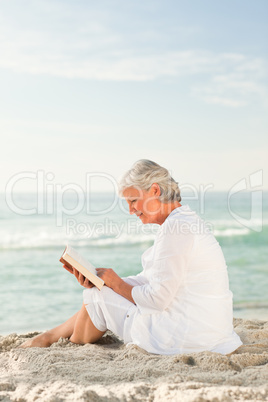 Elderly woman reading her book on the beach