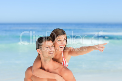 Handsome man having wife a piggyback on the beach