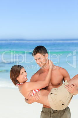 Man carrying his wife at the beach