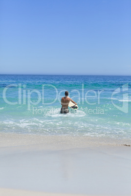 Man running on the beach with his surfboard