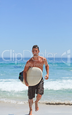 Man running on the beach with his surfboard