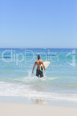 Man running on the beach with his surfboard