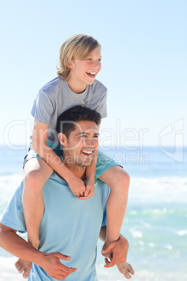 Father having son a piggyback at the beach
