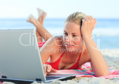 Lovely woman working on her laptop at the beach