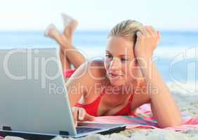 Lovely woman working on her laptop at the beach