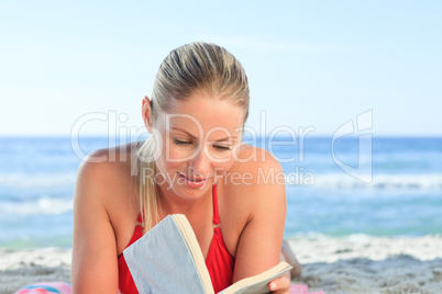 Adorable woman reading a book on the beach