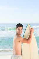 Handsome man beside the sea with his surfboard